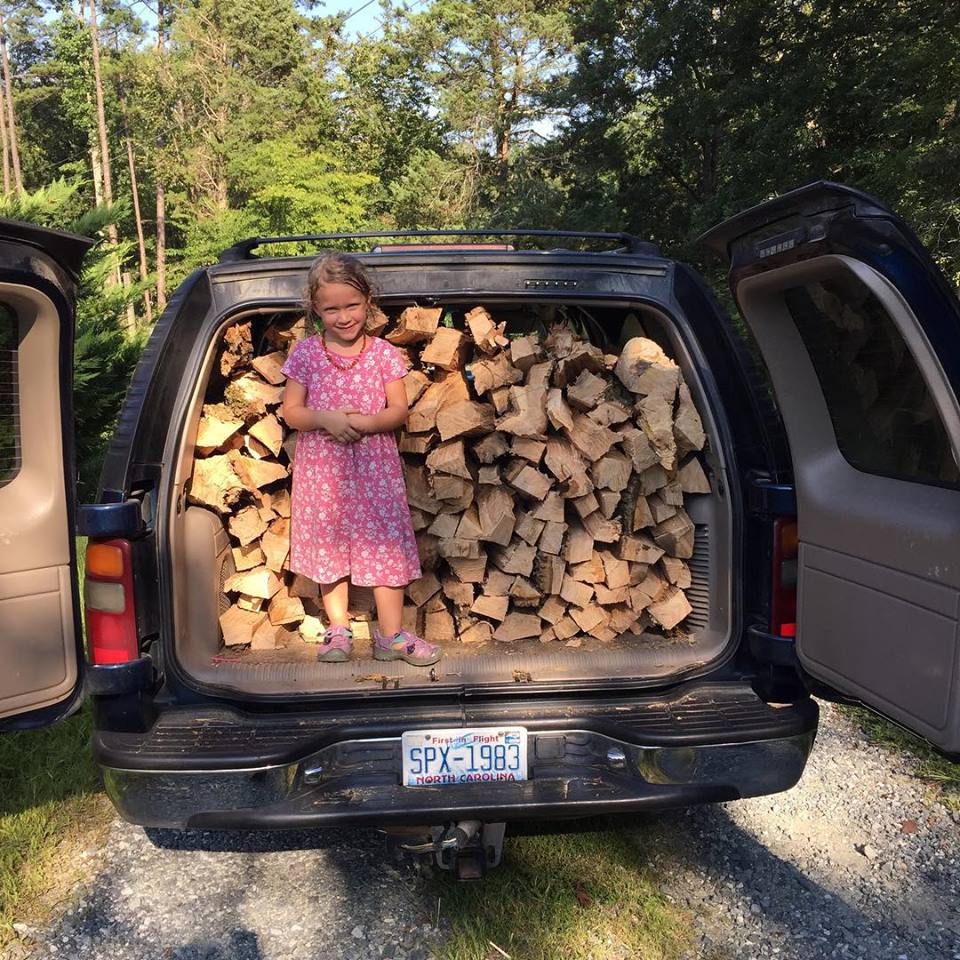 A girl in front of a stock pile of woods
